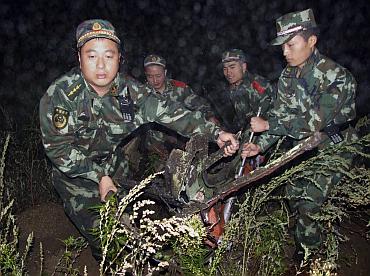 Paramilitary policemen carry the wreckage of a crashed passenger plane in Yichun, northeast China's Heilongjiang Province August 25, 2010