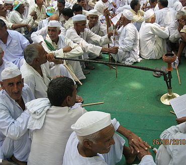 A farmer smokes his hookah as others sit beside him during the protest