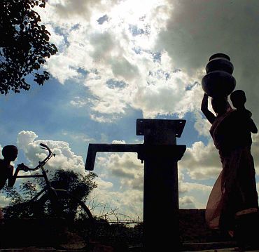 A women carries water pots at a well in a drought hit village in West Bengal