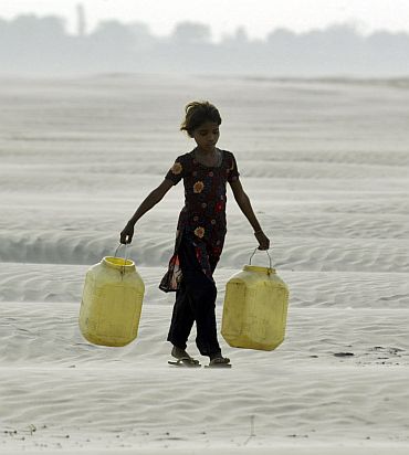 A village girl carries empty containers to collect drinking water near Chilla village in the Bundelkhand region of northern Uttar Pradesh