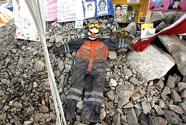 A miner's uniform lies on rocks along with letters and pictures to commemorate the 33 miners who are trapped underground