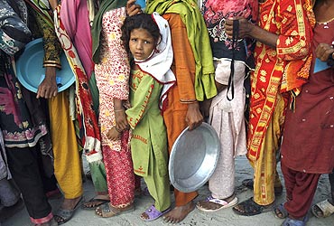 A flood victim stands in queue with others to get food handouts at a relief camp