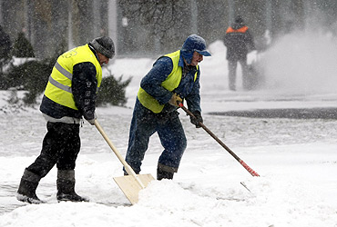 Men clear the snow away from a street in Warsaw