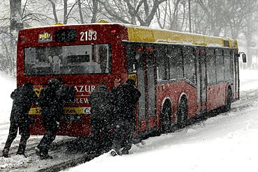 Passengers push a bus during heavy snowfall in Lublin, eastern Poland