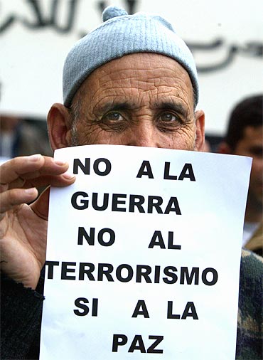A man holds a poster reading 'No War, No Terrorism, Yes to Peace' in Madrid