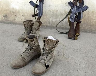 Afghan soldiers' boots with holes are left by a wall