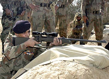 Kayani fires a sniper rifle during his visit to Tilla Field Firing Ranges