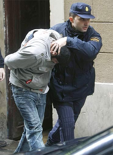 Police officers take an arrested man into a car after a police operation in Barcelona.