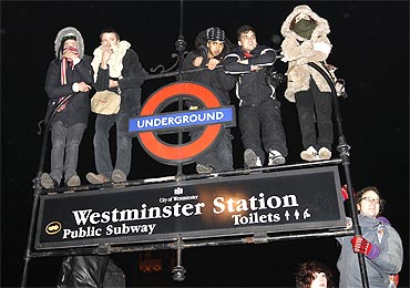 Demonstrators stand on an underground sign during a protest in Westminster