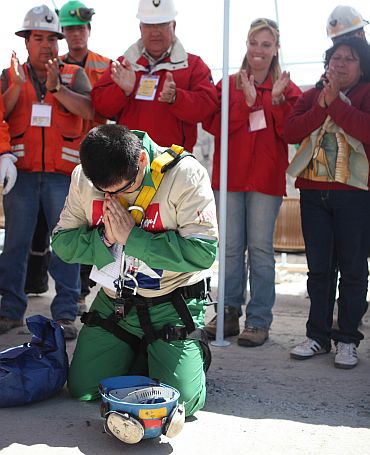 Trapped miner Esteban Rojas kneels to pray after reaching the surface