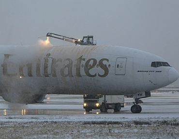 An Emirates aircraft is de-iced after heavy snowfall at Dusseldorf airport