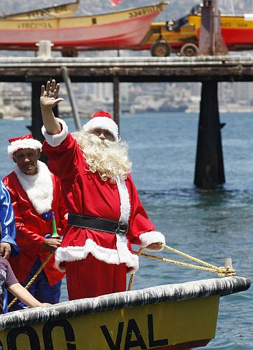 Ruben Torres, dressed in a Santa Claus outfit, and fishermen wave to people from a boat on Christmas Eve along the coast of Valparaiso city, about 75 miles (121 km) northwest of Santiago, the Chilean capital. Every year, fishermen in Valparaiso organise a Santa Claus boat trip as people wait on the shore to receive their Christmas presents and well-wishes