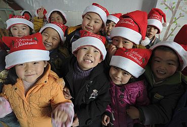 Children wearing Santa Claus hats pose for a photograph as they celebrate the Christmas Day at a kindergarten at Hefei, Anhui province of China