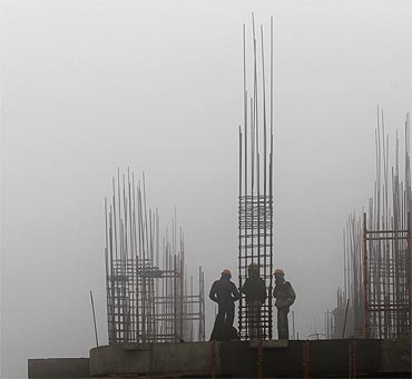 Labourers work at a construction site amid heavy fog near the airport in New Delhi