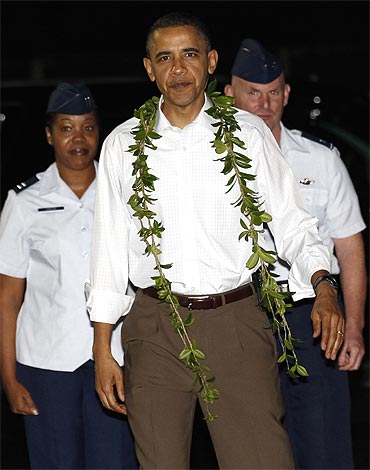 US President Barack Obama has a lei placed around his neck as he arrives for a vacation in Hawaii