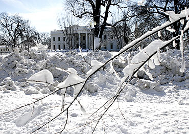 Plowed snow is seen along Pennsylvania Avenue, with the snow-covered White House in the background