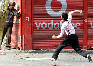 A Kashmiri protester throws a stone towards a policeman during a protest in Srinagar