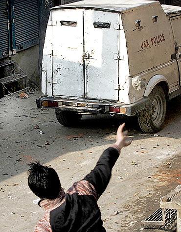 A protester throws a stone towards a police vehicle during a protest in Srinagar