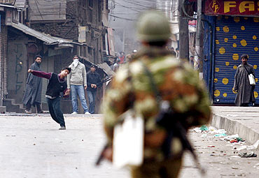 A Kashmiri protester throws a stone towards a policeman during a strike