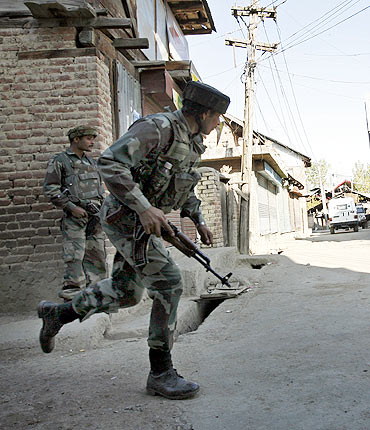 A soldier runs during a gun battle with militants in Sopore