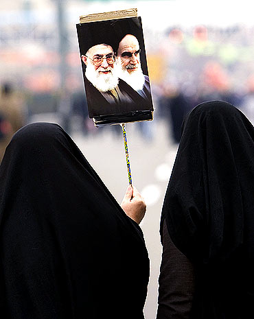 A woman carries a placard with the images of Iran's Supreme Leader Ayatollah Ali Khamenei (L) and founder of the Islamic Republic Ayatollah Ruhollah Khomeini