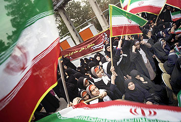 Schoolgirls wave Iran flags during a ceremony to mark the anniversary