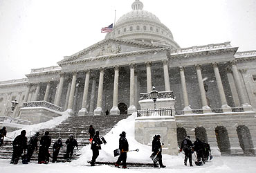 Workers clear snow from the steps of the US Capitol in Washington