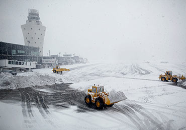 Heavy equipment is used to try to clear the tarmac as snow continues to accumulate during a 'Nor-Easter weather pattern bringing blizzard conditions to Laguardia airport, in New York