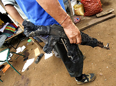 A policeman holds a burnt weapon at a police camp attacked by Maoist rebels