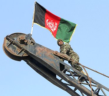 Private Aziz Watandosd, 22, of 2nd Company 1st Battalion, 201st Corp of the Afghan National Army looks on after climbing a crane to raise the Afghan national flag after removing the Taliban's white flag in the former Taliban stronghold of central Showal