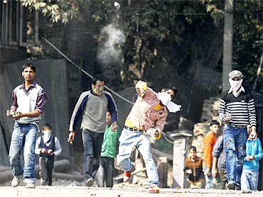 A Kashmiri protester throws a stone towards the police during a protest in Srinagar