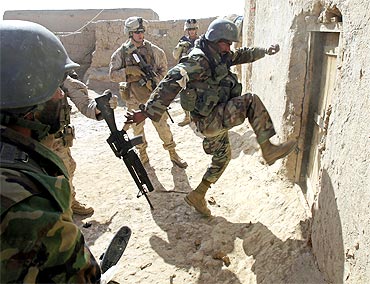 An Afghan soldier attempts to break open a door as US Marines look on during an operation in the town of Marjah in Helmand province
