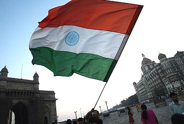 A peace activist waves the national flag in front of the Taj Mahal hotel in Mumbai