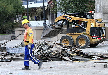 A municipal worker clears rubble from a street in Santiago after the quake.