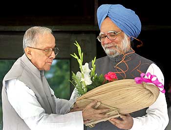 Jyoti Basu (L), hands a bouquet to Indian Prime Minister Manmohan Singh at his residence in Kolkata July 11, 2006
