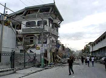 People walk along a street lined with buildings that were destroyed by the earthquake.