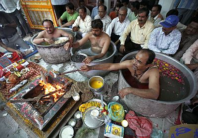 Priests sit inside cooking pots filled with water as they perform special prayers in order to appease Varun, the rain god, in the city of Ahmedabad in Gujarat on June 29, 2010.