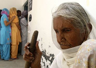 A woman waits to cast her ballot outside a polling station at Skatari village in Haryana