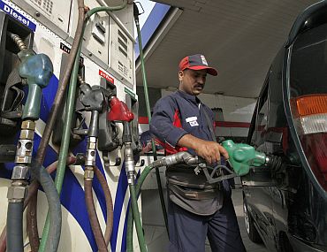 An employee fills a vehicle with petrol at a fuel station in New Delhi on June 25
