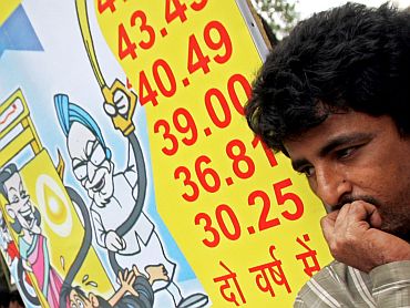 A Bharatiya Janata Party activist stands near a placard, which depicts the increase in petrol prices