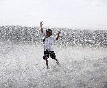 A boy enjoys himselfs as huge waves hit Mumbai's seafront during high tide