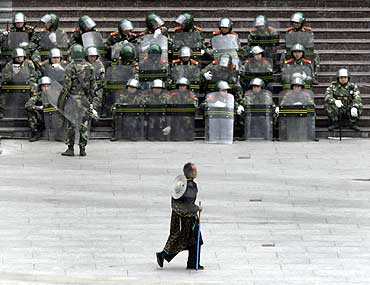 A Tibetan man walks past soldiers in the main square in Kangding city, China