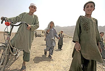 Afghan boys watch a US patrol team in Arghandab District, north of Kandahar
