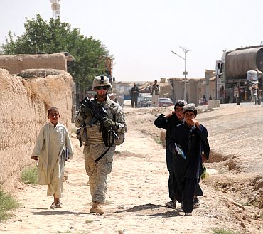 Afghan children walk alongside a US army soldier during a patrol in Zabul province, Afghanistan