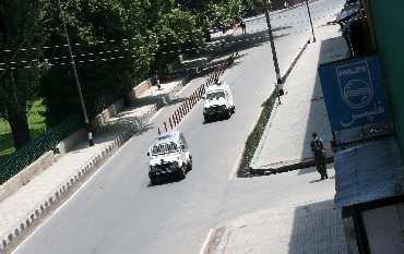 Army vehicles pass through a deserted road in Srinagar