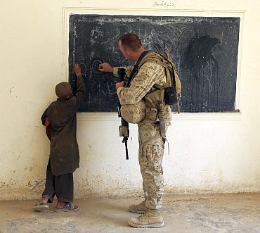 A US Marine writes on a chalkboard with an Afghan boy during a renovation planning visit at a school in the Nawa district of the Helmand province of Afghanistan