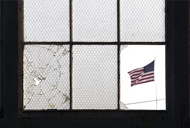 An Amercian flag flutters, when seen from a broken window from inside an unused airplane hangar in Guantanamo Bay
