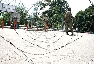 Police patrol behind concertina wire near martyrs' graveyard in Srinagar