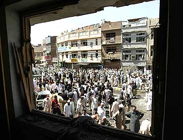 Pakistanis gather at the site of a bomb blast in Peshawar