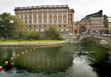 A fisherman lifts his net from a canal next to Sweden's Riksdagshuset, or Parliament building, in Stockholm